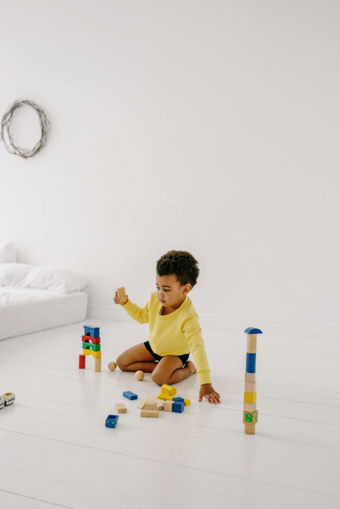 Young child in a bright room playing with colorful wooden blocks, creating a playful and serene atmosphere.
